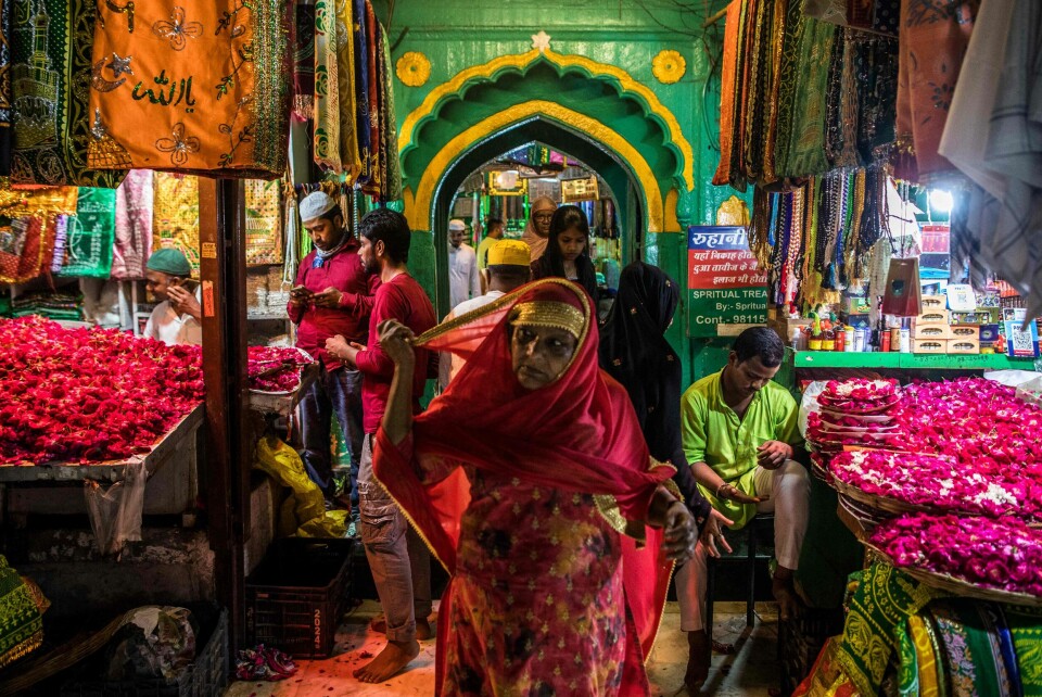 In this picture taken on September 15, 2022, devotees walk past vendors selling flowers and religious items at the Hazrat Nizamuddin Aulia Dargah Sufi shrine in New Delhi. - Religion plays a significant role in the lives of Indians and flowers have an equally pivotal role in the religious practices in the country. From Hindus to Muslims, the two largest religions in India, flowers and faith remain completely intertwined. India produces roughly 2,200 thousand tonnes of loose flowers, according to the federal horticulture department, nearly 70 percent of them are used in religious practices. The floriculture business was pegged at more than 230 billion rupees ($28 billion) in 2022. (Photo by Xavier GALIANA / AFP)
