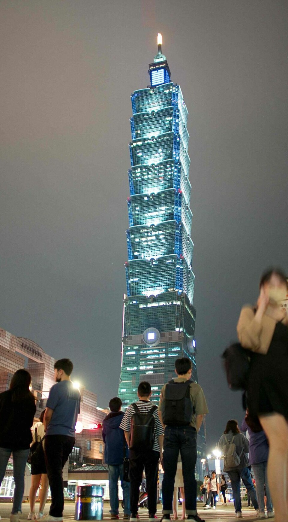 People walk past the Taipei 101 skyscraper in Taipei on April 28, 2023. (Photo by Sam Yeh / AFP)