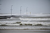 Rough sea waves pounding a pier with streetlights at Løkken during Storm Dave.