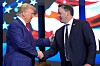 Donald Trump shakes hands with Georgia Lt. Gov. Burt Jones on a stage with a U.S. flag backdrop.